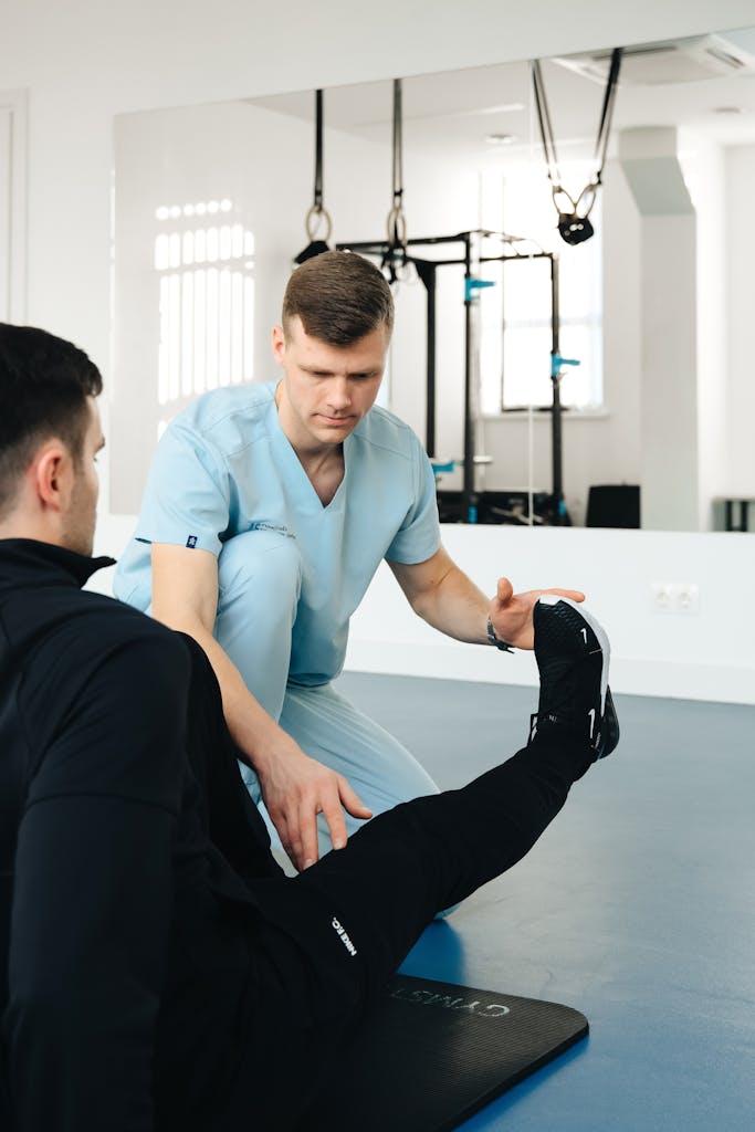 Experienced physiotherapist helps patient stretch leg in a modern clinic setting, focusing on rehabilitation.